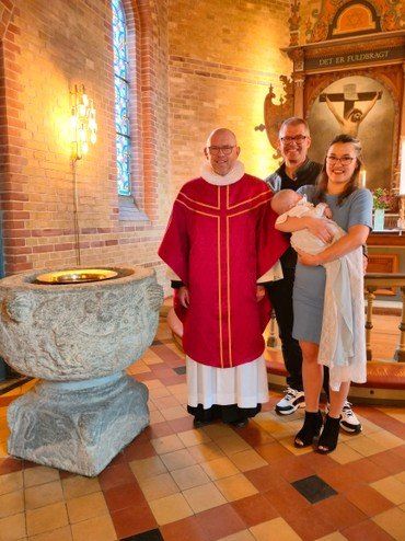 Billede af familien til dåbsbarn sammen med præsten.